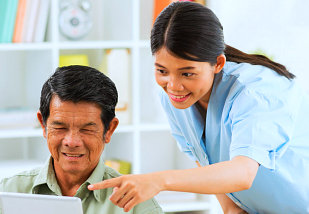 caregiver pointing at the tablet screen used by senior man