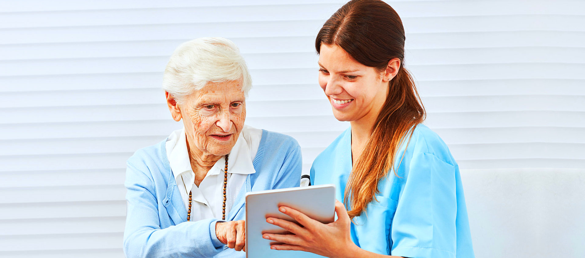 caregiver and senior woman looking at the ipad