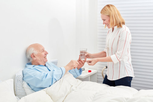 caregiver offering senior man water